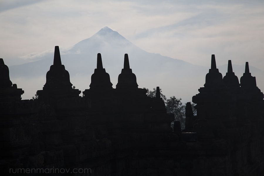 Dark stupas of Borobudur with Mt Merapi in the background.